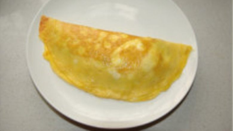 简易蛋包饭#挑战鸡蛋的100种做法#,将另外一半蛋皮对折裹住米饭，边沿压实，略煎成型出锅即可。根据个人口味可在表面挤上番茄酱。