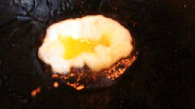 米饭蛋饺#挑战鸡蛋的100种做法#,锅里倒入一点油，用汤勺舀一勺放入锅里，全程都要小火