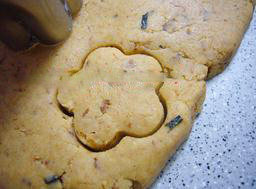 芝麻肉松饼干,取出面团，擀成1cm左右的薄片，用饼干模压出花型，放在垫了油纸的烤盘上，撒上芝麻。