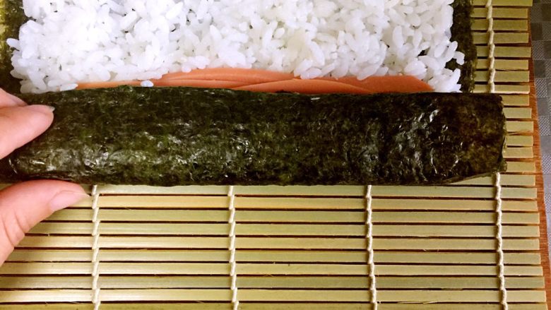 家庭版简单寿司,6、三分之一处铺上火腿条、黄瓜条、胡萝卜条，随意哈
7、卷起来，手上带点劲儿别让寿司卷太松
