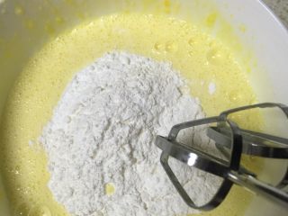 酸奶小蛋糕,筛入玉米淀粉和低筋面粉，搅拌直至无干粉成为细腻的蛋黄糊