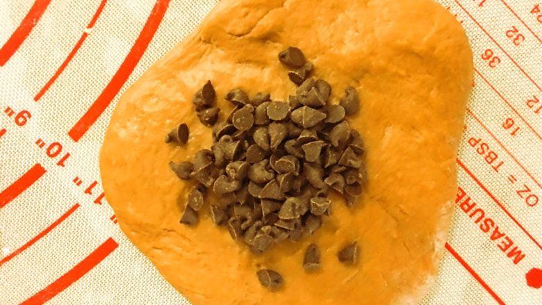 好吃到飞起来的黑眼豆豆,醒发好的小面团依次压平，包上5g巧克力豆，收口向下，揉成团。