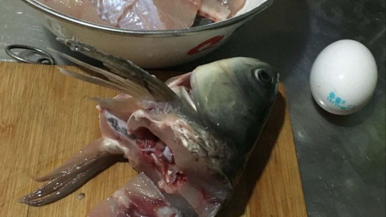 妈妈厨味—回锅鱼,4.鱼头鱼尾留下备用，看见那白瓷盆了没，把刚切的鱼片抹上盐放入盐和料酒腌制片刻，再放鸡蛋清和淀粉腌制。