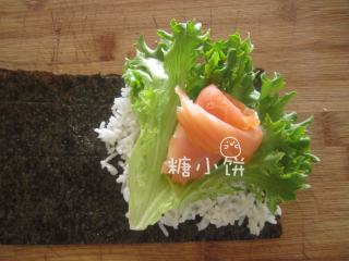 烟熏三文鱼手卷,在铺米饭的位置上铺上一片洗净的卷叶生菜，抹一点芥末膏，再摆上三文鱼卷。