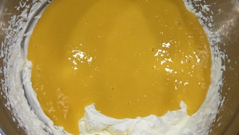 免烤芒果慕斯蛋糕,将加了吉利丁片的芒果糊倒入打发好的淡奶油中。