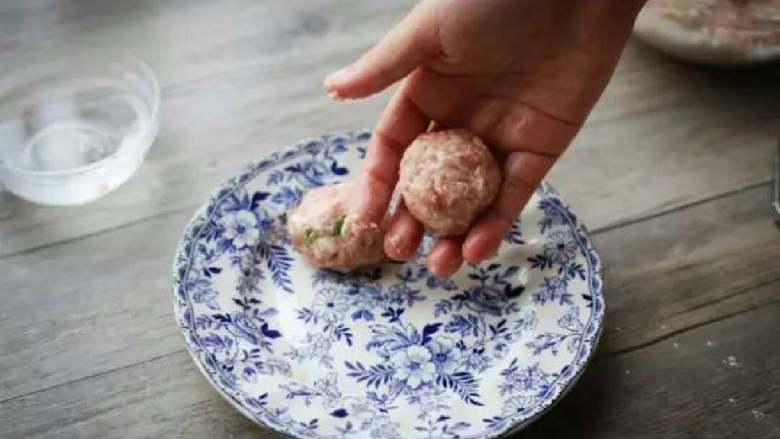 猪肉丸,将搅拌后的肉碎在两掌之间揉成球状、成型后放入碟子中。