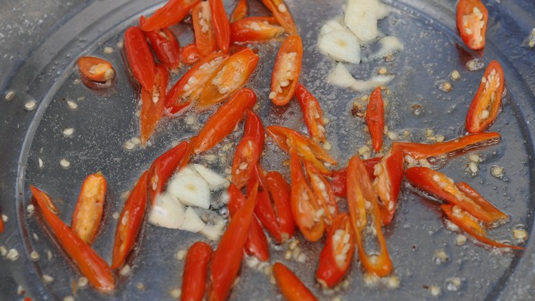 尖椒炒藕片,锅中油热后将蒜片和尖椒爆香。