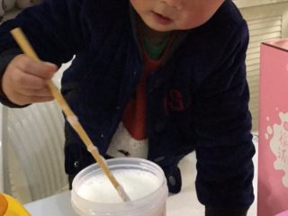 自制草莓酸奶,用筷子把倒入的乳酸菌跟牛奶搅拌均匀