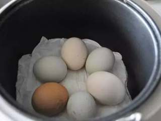 煮蛋,等电饭锅自己蹦到保温，就行啦！看，纸上的水已经干了，鸡蛋熟啦！