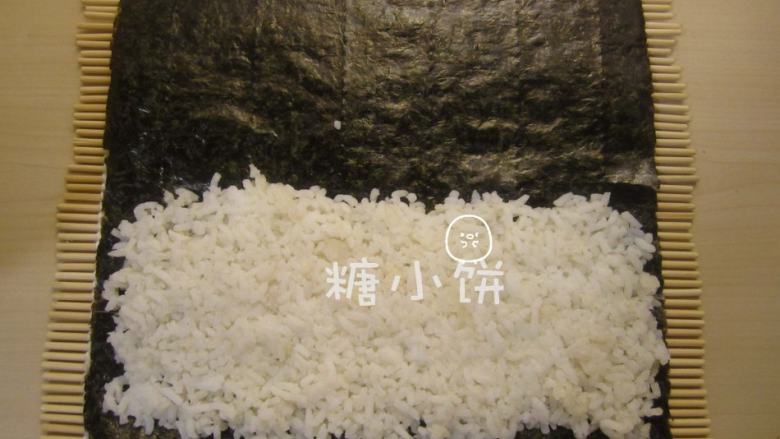 玉米笋细卷,在靠下端的一半铺上米饭。因为是细卷，米饭不要铺太多，一半就够如果用半张紫菜的话还可以再少铺一点，堪堪够包裹住夹馅的食材就行。