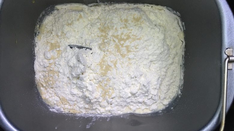 乳酪火腿面包,除黄油以外的所有面团材料按先液体后粉类的顺序投入面包机，启动一个和面程序。