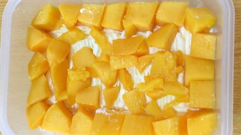 水果便当蛋糕 #乐享双节#,摆上一层芒果粒，规整的尽量放四周一圈，中间放些碎粒即可。