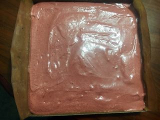 红丝绒蛋糕#乐享双节#,倒入垫了油纸的烤盘里，大致地抹平表面，震动几下，震出大气泡