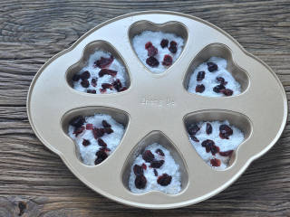 桂花蔓越莓松糕,把過篩好的粉用勺子兜入模具大約到一半位置，撒一層蔓越莓干。