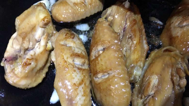 咖喱鸡翅焖饭,煎好的鸡翅盛出，锅内放入蒜片炝锅，再倒入鸡翅翻炒，加入适量酱油。