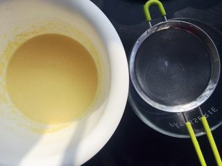 港式下午茶首选的芒果班戟,继续搅拌，完全混合后过筛到无水无油的干净容器里。盖上保鲜膜放入冷藏室冷藏半小时。