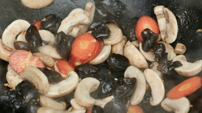 口菇烩豆腐,锅中留油，将姜片爆香后放入口菇、胡萝卜和黑木耳。