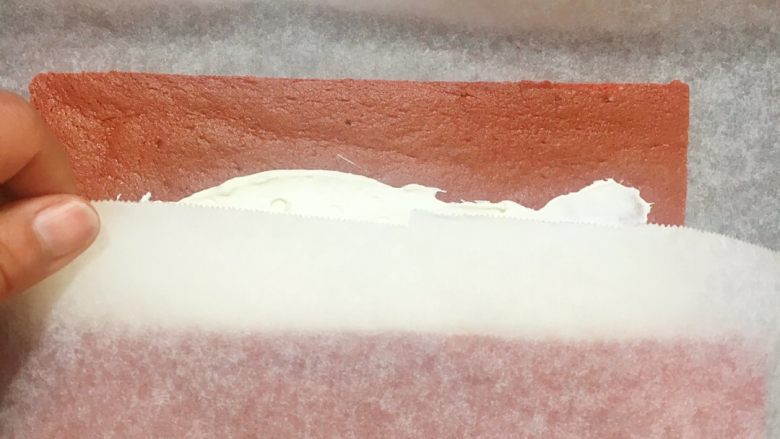 红丝绒棉花蛋糕卷,这次就不要连纸一起卷进去哦，等卷到一半时放开油纸徒手卷，因为刚才已经有过定型，很好卷起来的