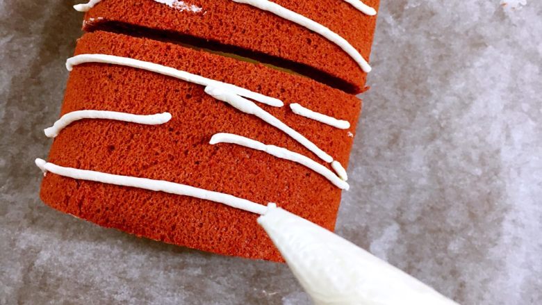 红丝绒棉花蛋糕卷,把蛋糕卷切成几段，大小随君意，剩余的奶油装入裱花袋，剪个小口，细细地划拉几根线条