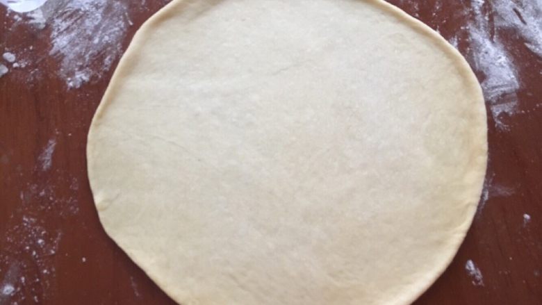 蓝莓夹心网纹面包,取一个面团擀成圆片，大小和八寸披萨模底一样大，一定要擀的时候超过这个尺寸才行，因为放到模具里的时候会回缩，总之放进去的时候和模具一样大小就行