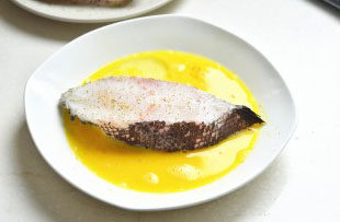 香煎杏仁鳕鱼,腌好的鳕鱼放在打好的蛋液中先均匀的裹上一层；
