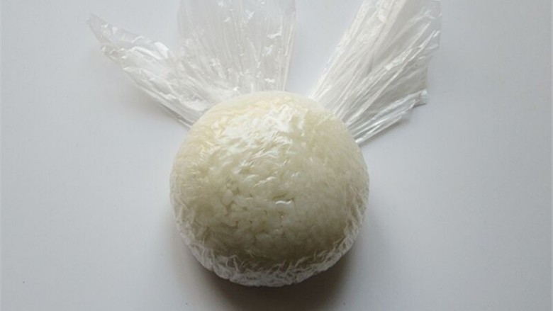 米菲兔杯子趣味餐,把米饭用保鲜膜握紧团起来，揉成一个球形饭团做头部主体部分
