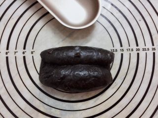 黑可可热狗包,取一小份面团，擀成椭圆形，两边向中间卷起，收口捏紧，搓成橄榄形