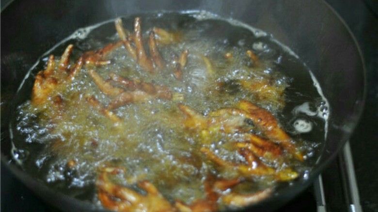 虎皮鸡爪,摇晃锅子，让鸡爪均匀泡在油里，待锅不再爆油时，揭开盖子，炸至皮紧发硬出纹
