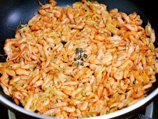 独家韭菜炒河虾,接着放入小河虾，中小火不断翻炒，把小河虾的水分煸出，再转中大火炒至酥香。
