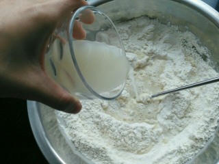 ≈刀切馒头≈,将混合均匀得酵母糖水倒入到面粉当中，边倒边搅拌