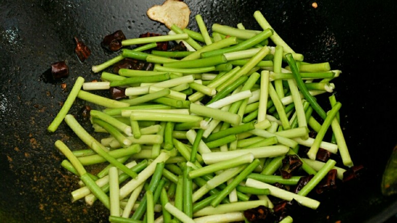 蒜苔肉丝#春意绿#,辣椒微糊放入蒜苔，炒至断生。