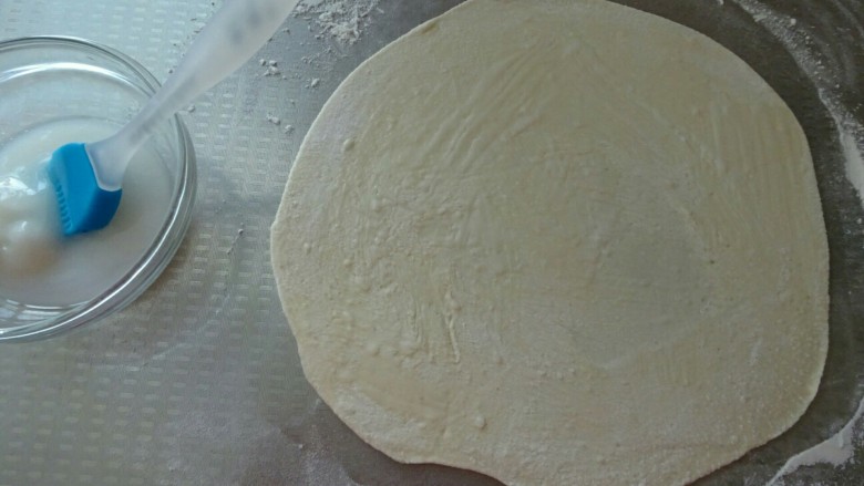 香酥葱花饼,取一份面团，按扁、擀成薄片，刷上一层猪油（尽量薄一点哦，这样卷起来才会层次多，口感好）