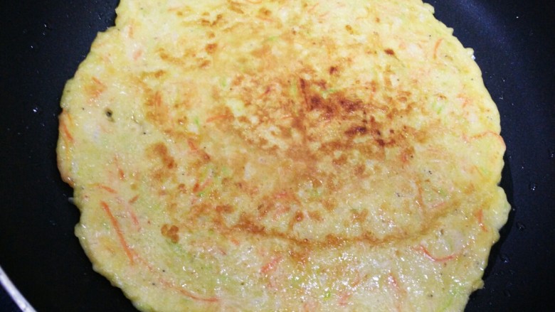 虾皮角瓜胡萝卜丝蛋饼,轻轻晃动不粘锅饼动了，表面干了就可以翻面了。