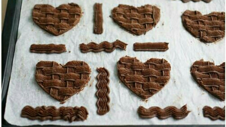 心形巧克力编织饼干,１１：取出后用饼干模压出爱心形状，刮掉边缘多余面团。
