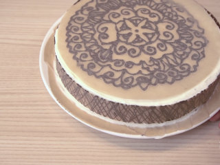 可可戚风 巧克力围边奶油蛋糕（视频菜谱）,等巧克力稍凝固，但没有完全变硬时，把花纹粘在蛋糕上，再放入冰箱冷藏5-10分钟