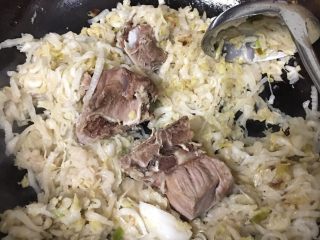 东北酸菜炖排骨,把煮好的排骨放进锅里和酸菜一起炒