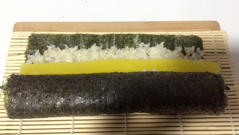 酱香味秋葵寿司（纯素版）,打开竹席放一根大根，继续用竹席卷上，并用力