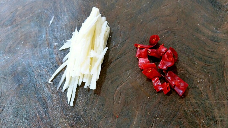 泥蒿炒腊肉,姜在案板上切细丝，干辣椒切成段，然后把干辣椒里面的籽去除，以免炒制菜肴时影响美观。