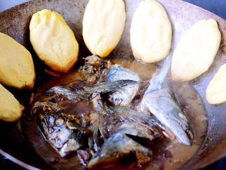 鱼头锅片片#烟台特色#,鲅鱼头烧开后、把醒发好的玉米团做成圆形薄饼子，烀至锅边、如图