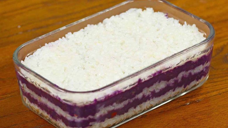 紫薯糯米糕,再铺一层糯米饭,抹平。就这样一层糯米饭一层紫薯馅，盛满为止。