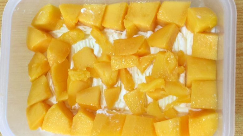 水果便当蛋糕,摆上一层芒果粒，规整的尽量放四周一圈，中间放些碎粒即可。