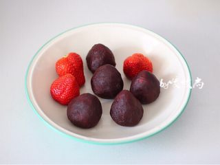 草莓大福,将草莓放在红豆沙饼上，戴上一次性手套将红豆沙均匀的裹住草莓。
