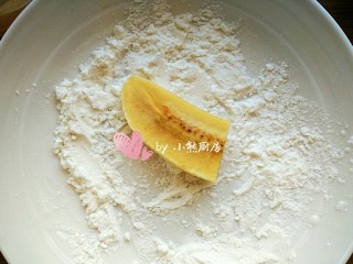 燕麦脆皮香蕉卷,将一个香蕉段放入淀粉中，左右翻滚，让香蕉均匀的裹上淀粉