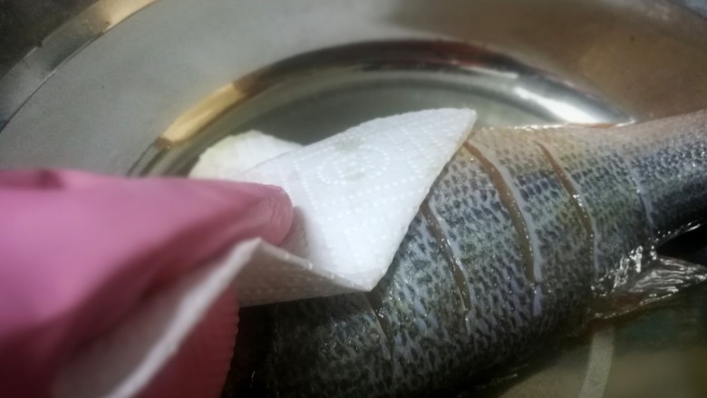 锡纸包烤鲈鱼,这个时候鱼也腌制差不多了，拿出来用厨房纸巾吸干水分，没有的可以控干水后拍点粉，因为要下油煎如果有水会炸油哦