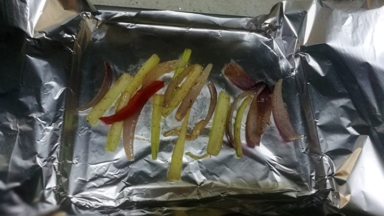 锡纸包烤鲈鱼,取锡纸折在烤盘中，把之前炒好的洋葱西芹放一点垫底