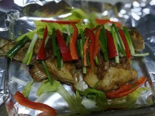 锡纸包烤鲈鱼,切好的红椒丝、葱段摆在鱼身上