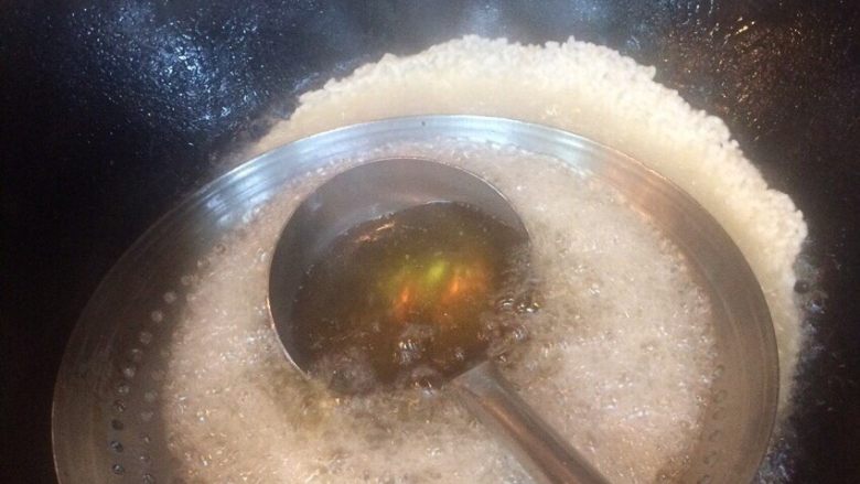 油炸锅巴,加热油      第一勺热油浇在漏勺上面流下去  不然一勺热油下去会把大米冲乱       后用漏勺把大米压压这样厚度容易均匀点  全程大火