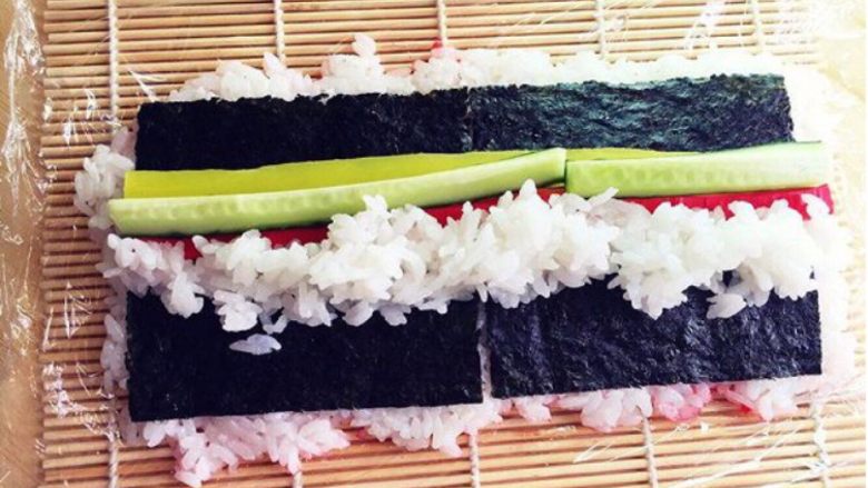 樱花寿司,掀开上面保鲜膜，将大根、黄瓜条、蟹肉棒排在上面，在一侧加上寿司米饭。