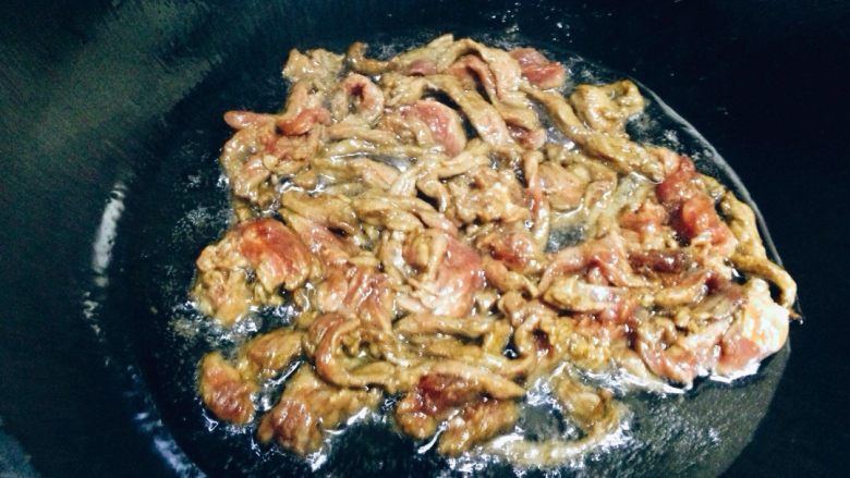 尖椒牛肉,转中火后将牛肉入锅滑散，翻炒至肉丝变酱白色。