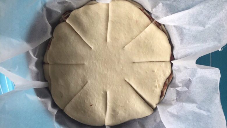 豆沙手撕花样面包,然后将面饼胚连同油纸一起放入圆形烤盘中，或者披萨盘都可以。